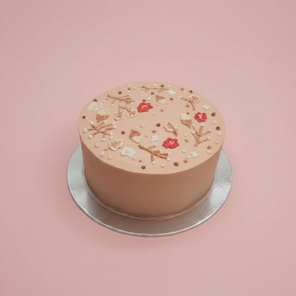 Small round cake with decorative elements on a marble surface